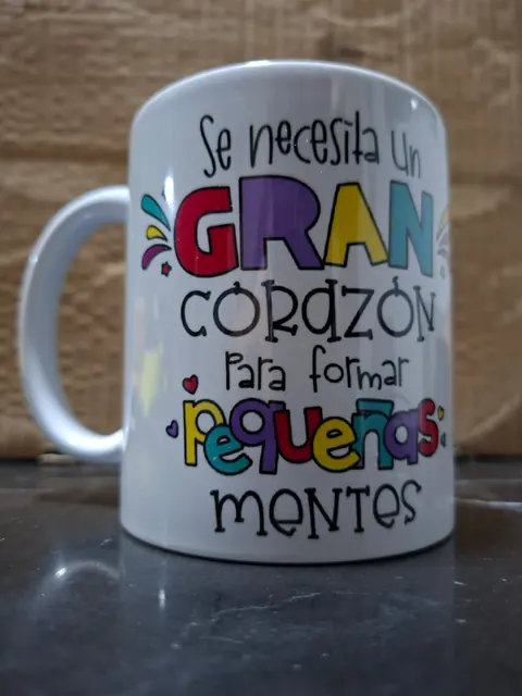 Taza blanca sublimada con la frase «Se necesita un gran corazón para formar pequeñas mentes» en letras de colores